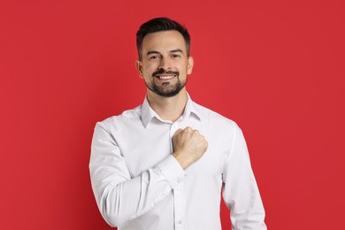 Photo of Man making promise on red background. Oath gesture