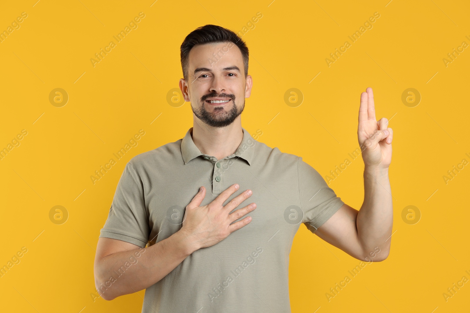 Photo of Man showing oath gesture on orange background. Making promise