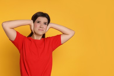 Photo of Woman covering her ears on orange background, space for text