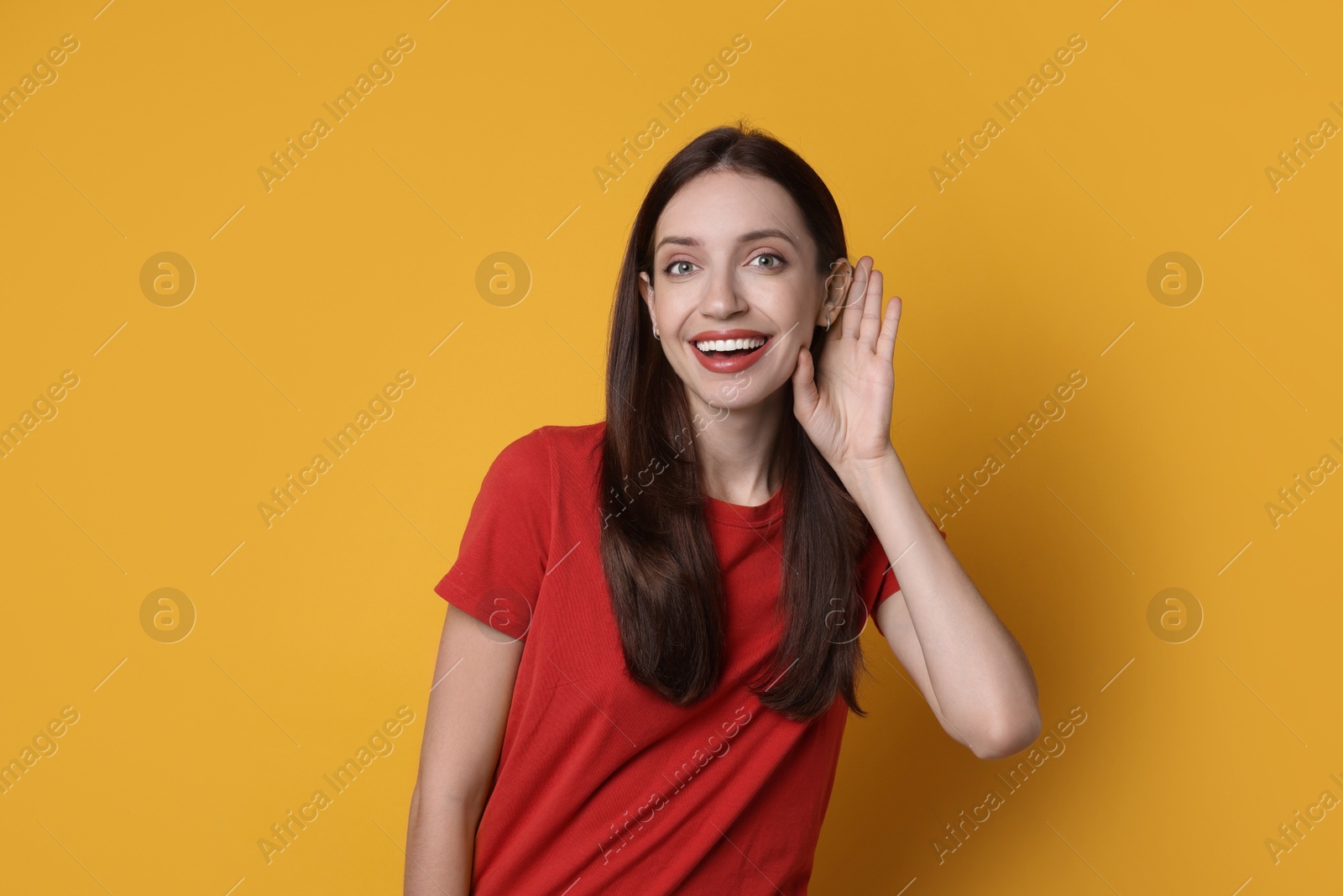 Photo of Woman showing hand to ear gesture on orange background