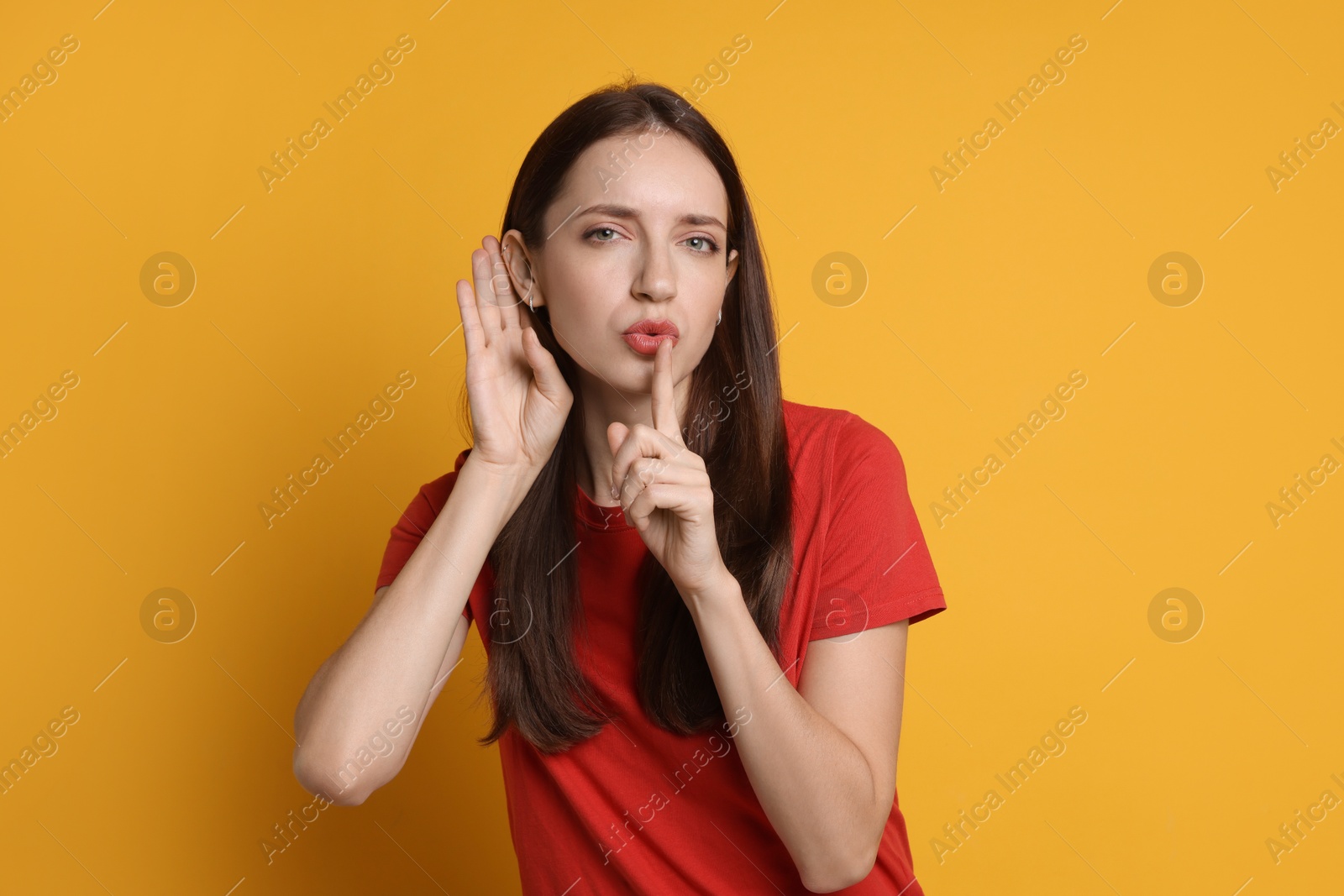 Photo of Woman showing hand to ear gesture on orange background