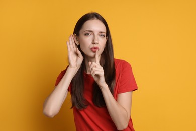 Photo of Woman showing hand to ear gesture on orange background