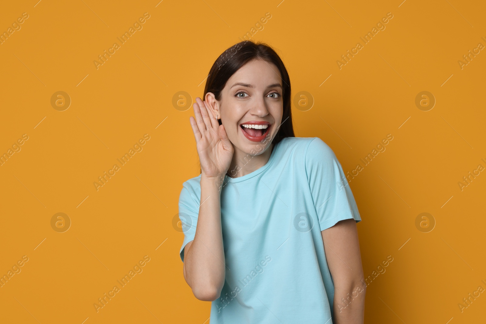 Photo of Woman showing hand to ear gesture on orange background