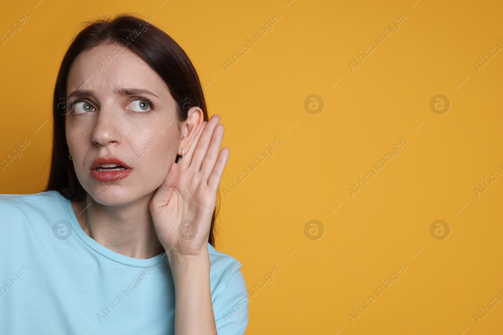 Photo of Woman showing hand to ear gesture on orange background, space for text