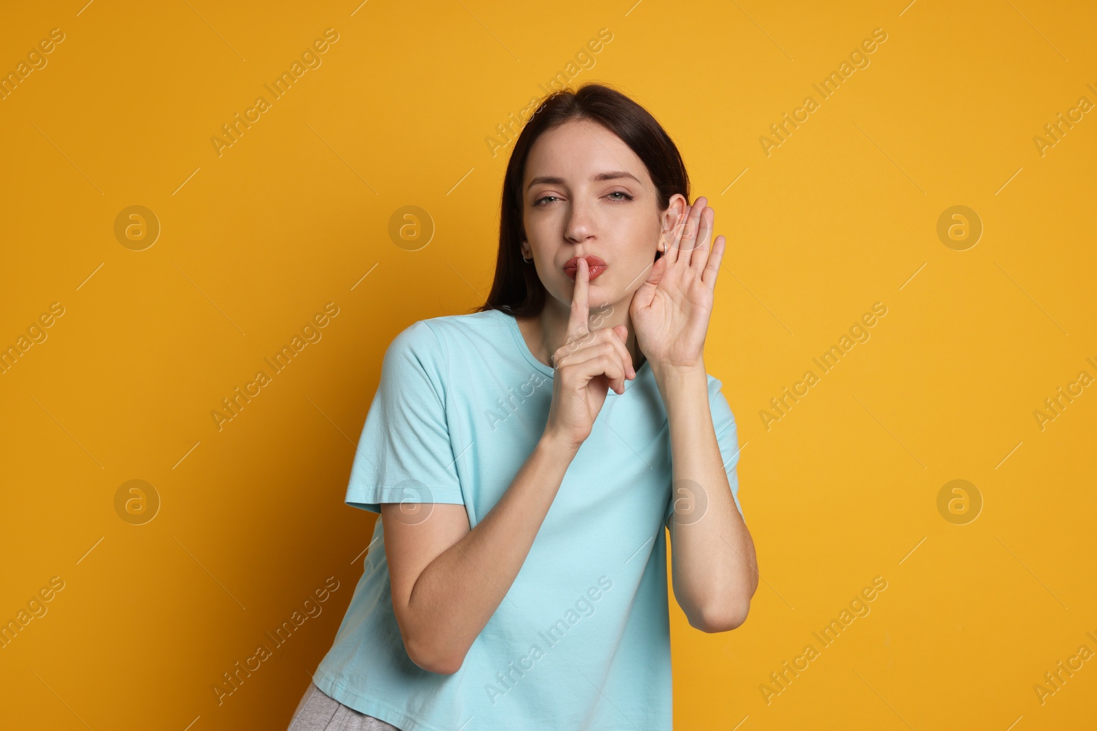 Photo of Woman showing hand to ear gesture on orange background