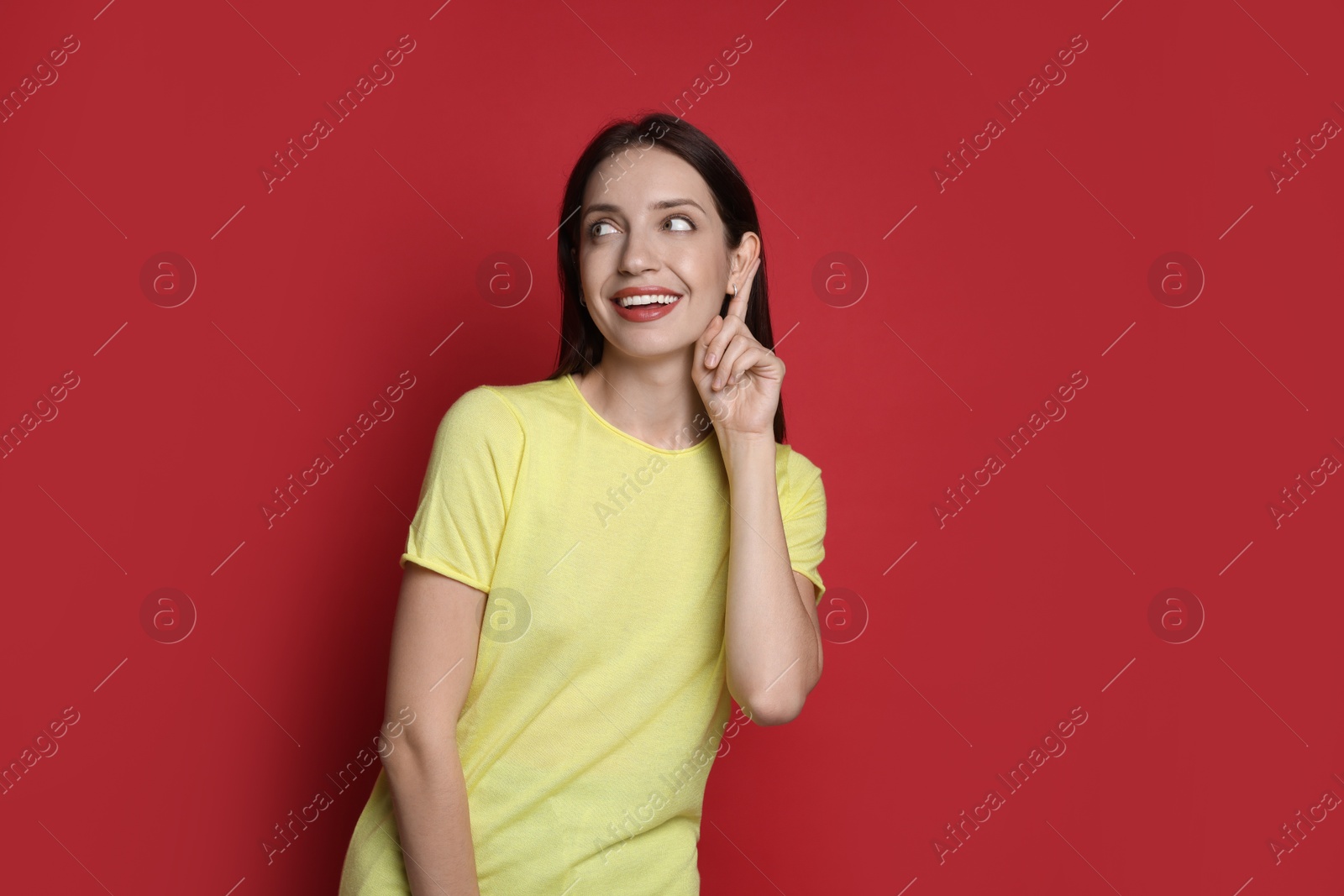 Photo of Woman showing hand to ear gesture on red background