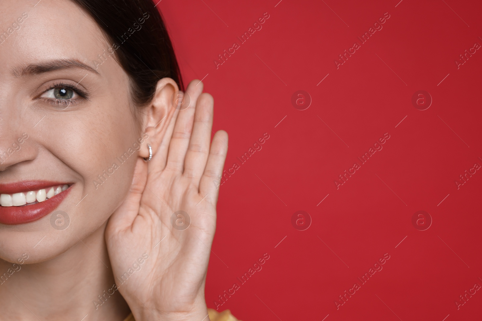 Photo of Woman showing hand to ear gesture on red background, closeup. Space for text