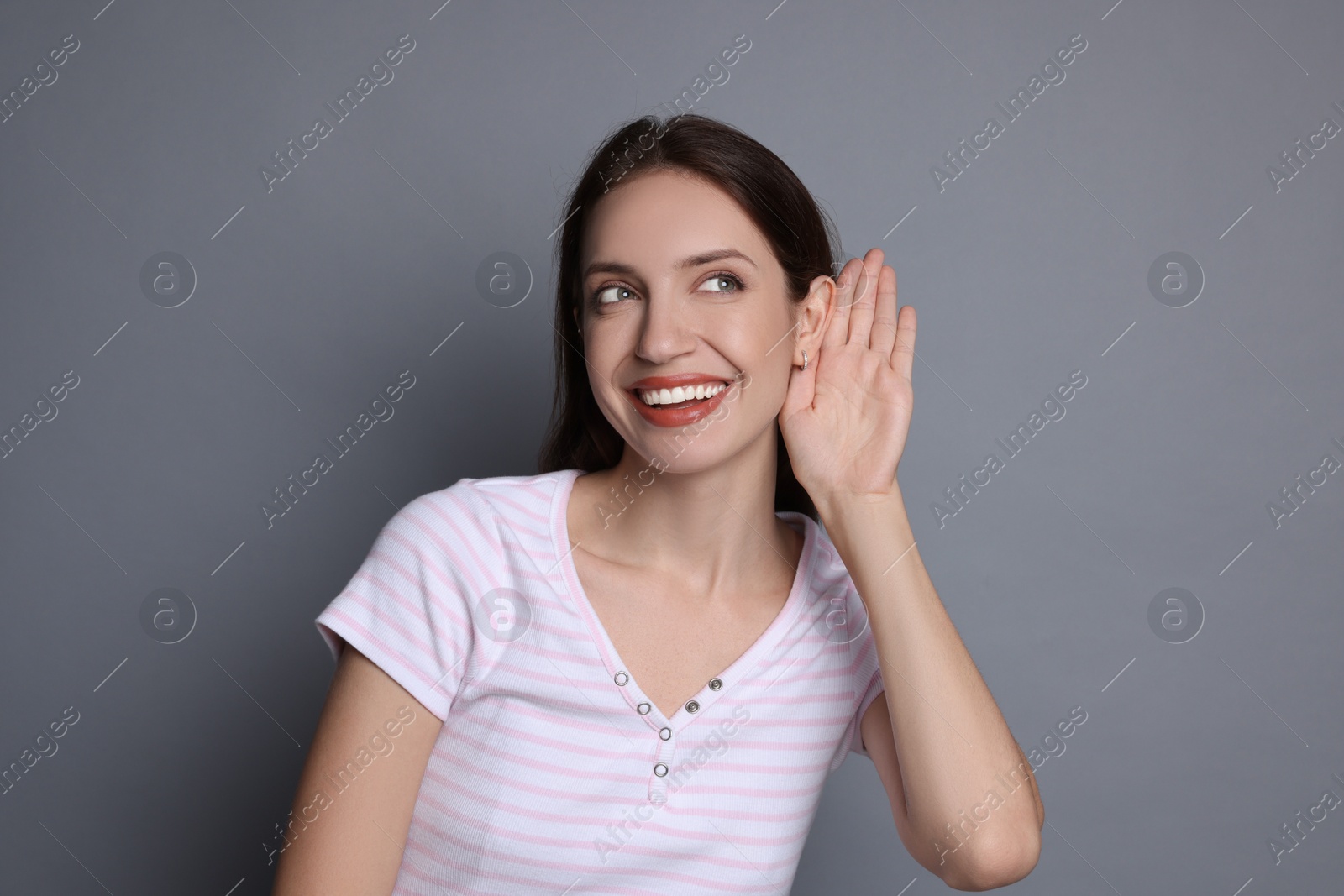 Photo of Woman showing hand to ear gesture on grey background