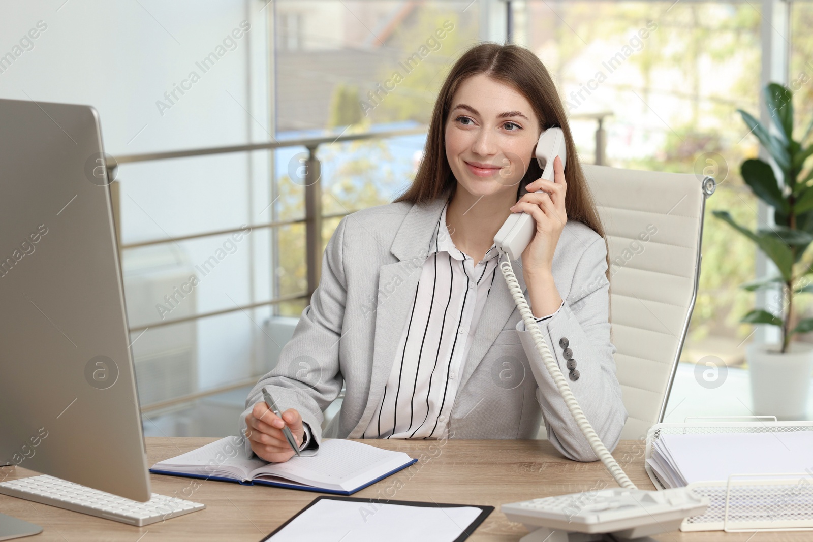 Photo of Banker talking on telephone at table in office