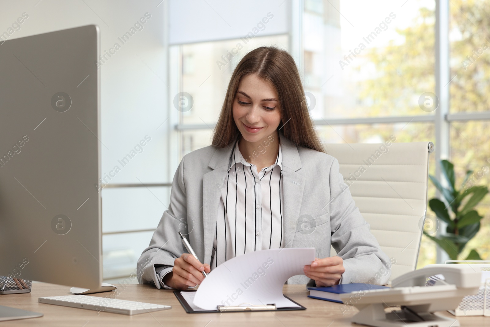 Photo of Banker with clipboard working at table in office