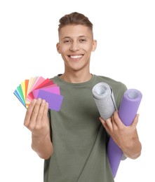 Photo of Young decorator with color palettes and rolls of wallpaper on white background