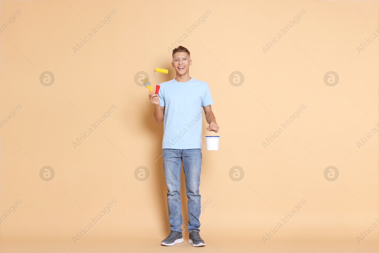 Photo of Young decorator with different tools on beige background