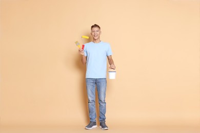 Photo of Young decorator with different tools on beige background