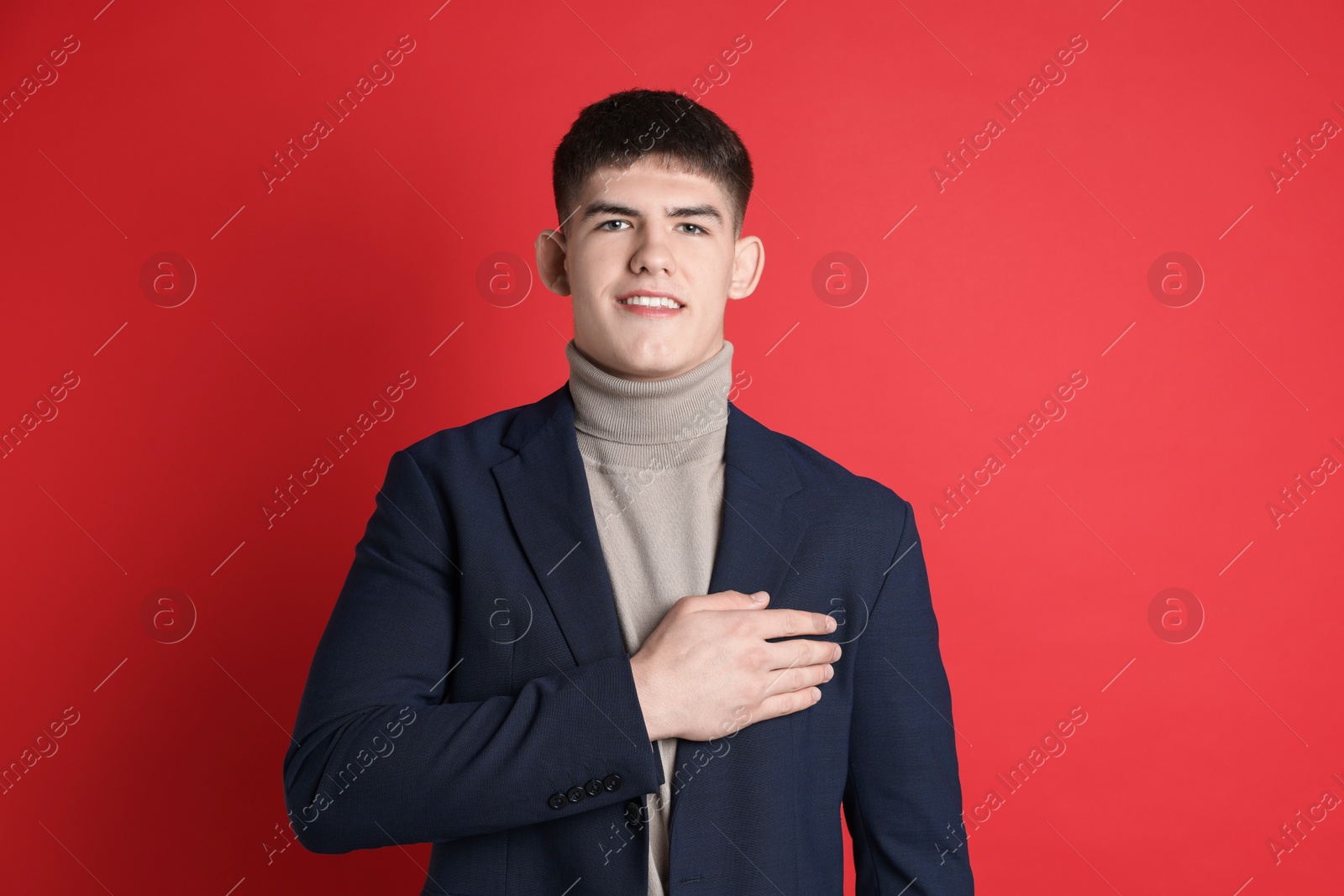 Photo of Man making promise on red background. Oath gesture