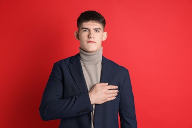 Photo of Man making promise on red background. Oath gesture