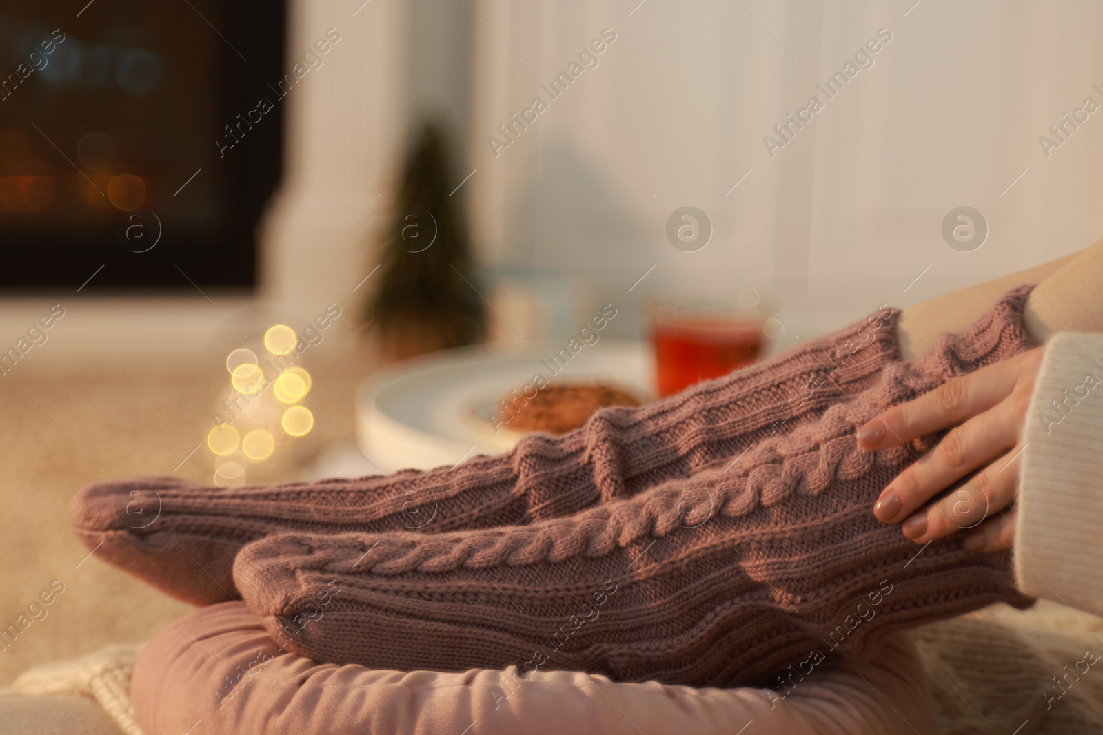 Photo of Woman in knitted socks resting at home, closeup