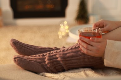 Woman with cup of tea resting at home, closeup