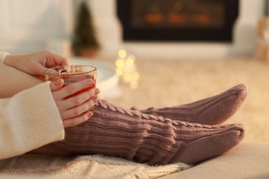 Woman with cup of tea resting at home, closeup