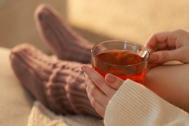 Woman with cup of tea resting at home, closeup