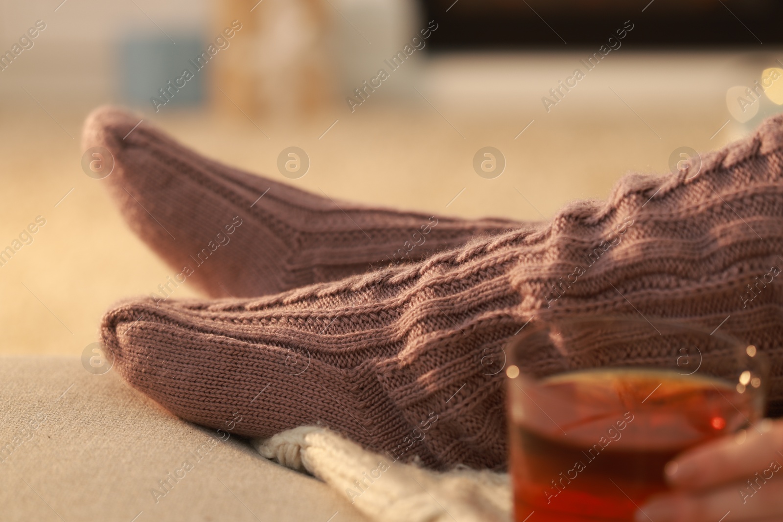 Photo of Woman in knitted socks resting at home, closeup