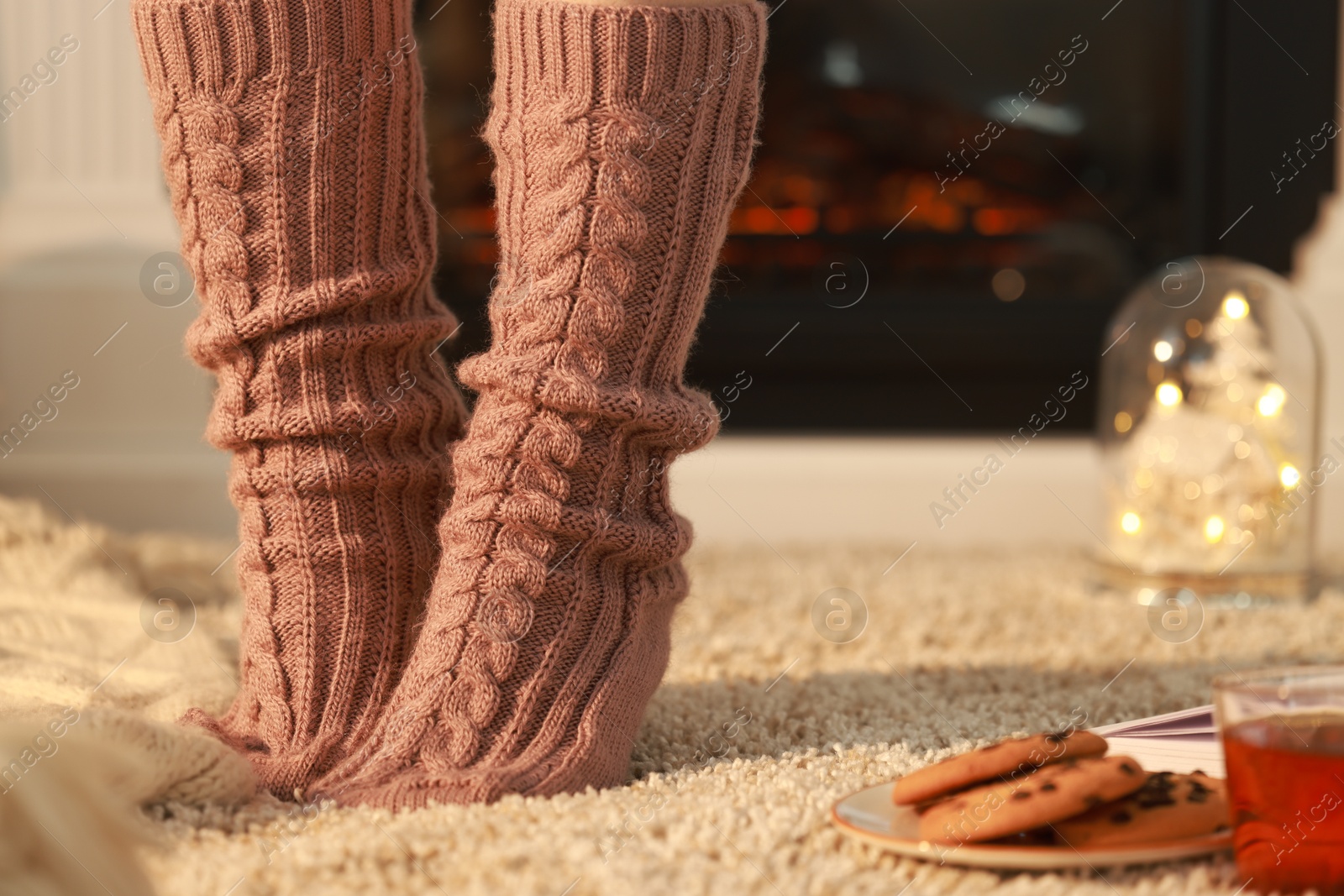 Photo of Woman wearing knitted socks at home, closeup