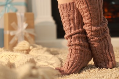 Woman wearing knitted socks at home, closeup. Space for text