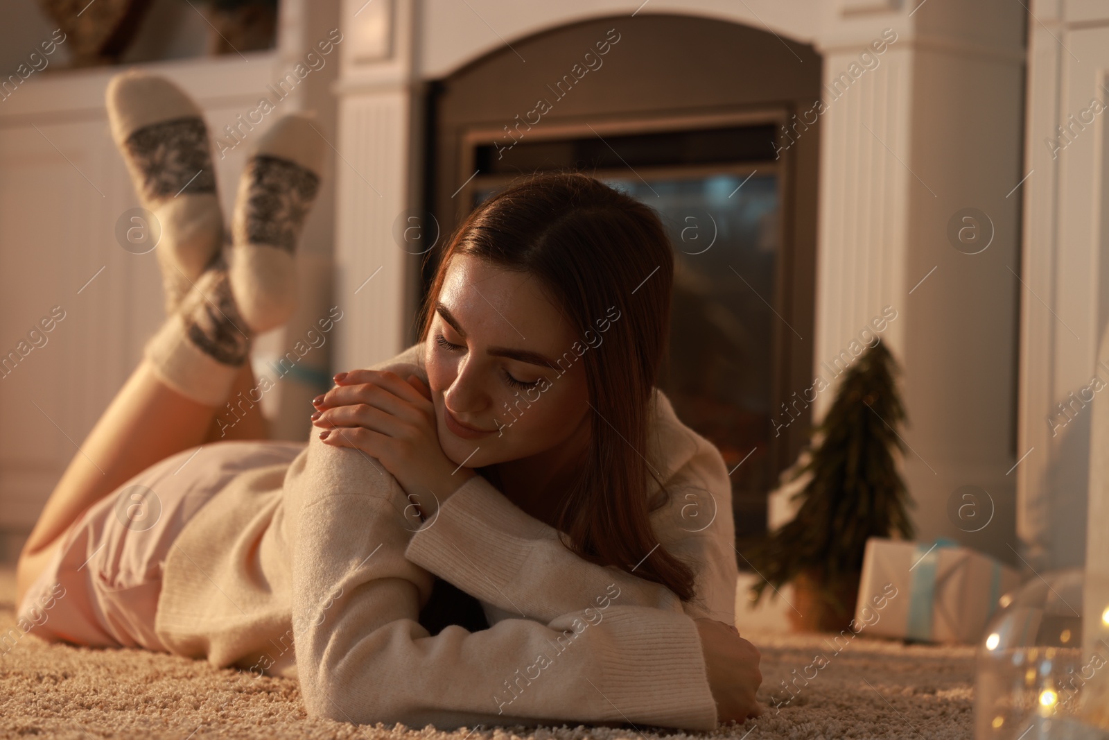 Photo of Woman in warm socks resting near fireplace at home