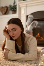 Photo of Woman in warm sweater resting on rug at home