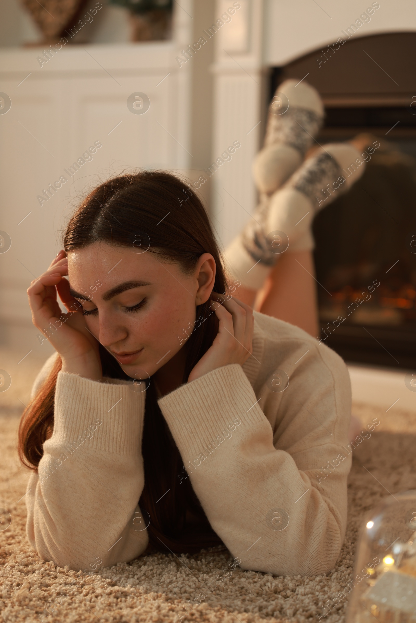 Photo of Woman in warm sweater resting on rug at home