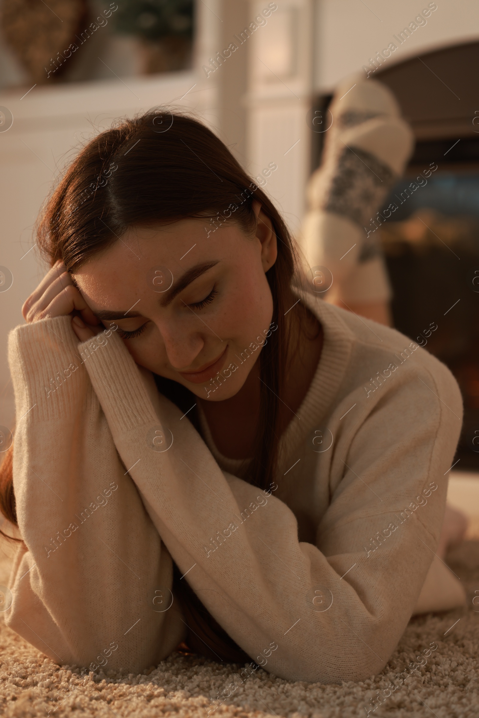 Photo of Woman in warm sweater resting on rug at home