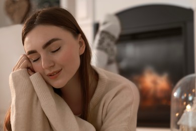 Photo of Woman in warm sweater resting near fireplace at home