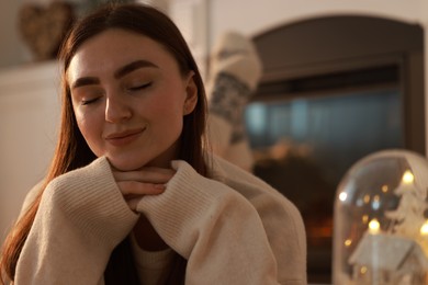 Photo of Woman in warm sweater resting near fireplace at home