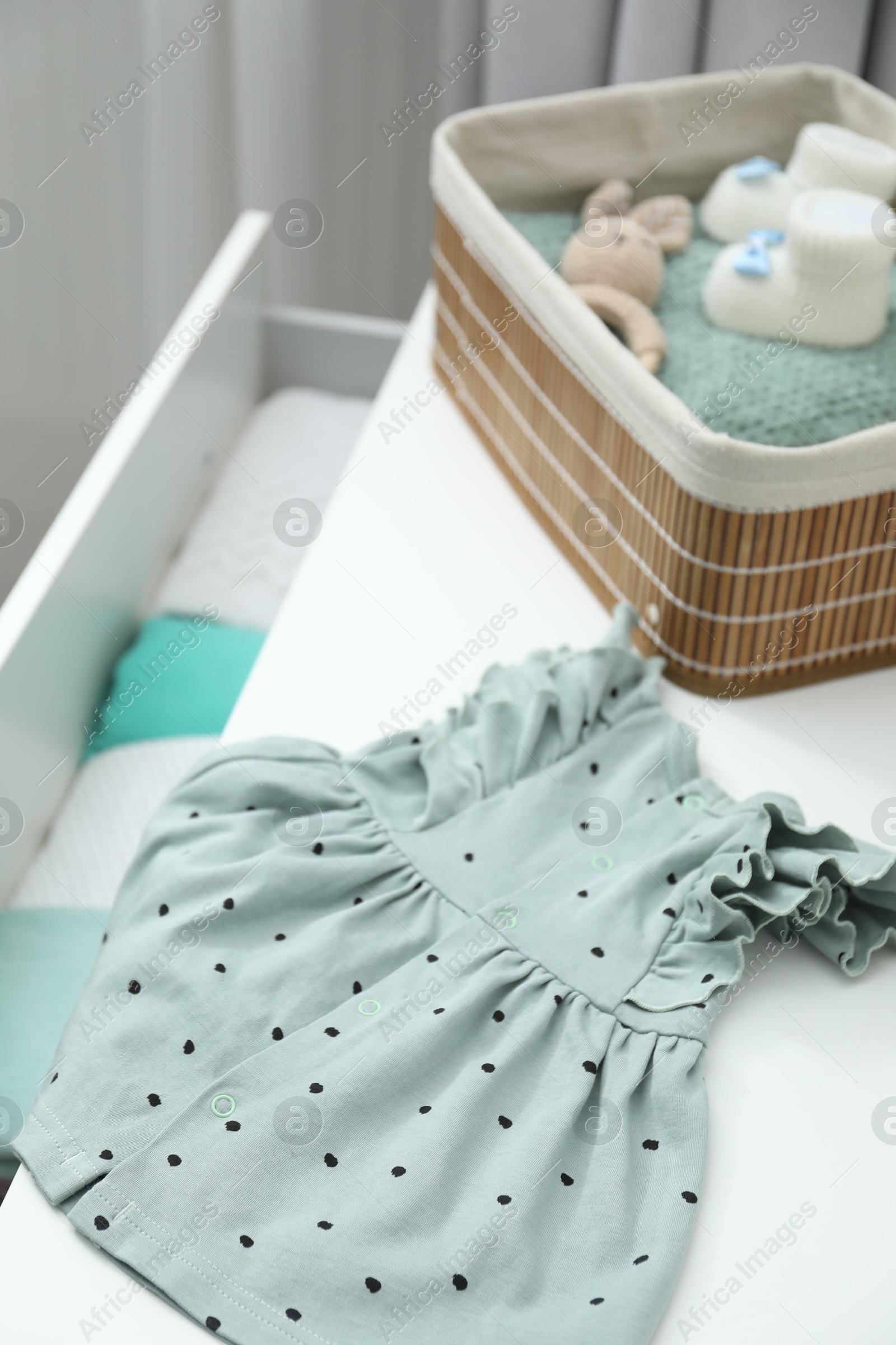 Photo of Baby clothes on white chest of drawers, closeup