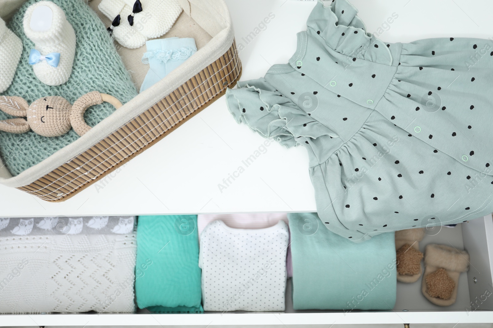 Photo of Baby clothes on white chest of drawers, top view