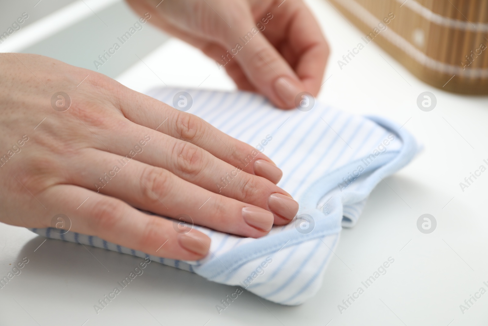 Photo of Woman folding baby clothes at home, closeup