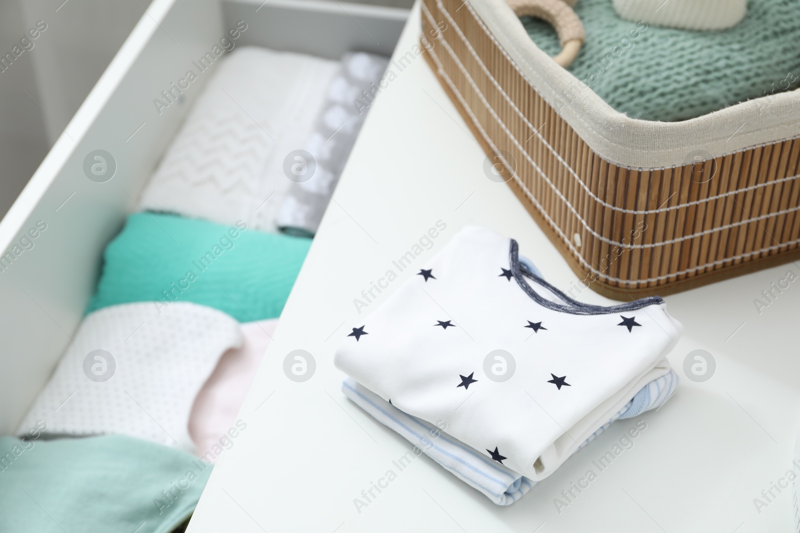 Photo of Baby clothes on white chest of drawers, closeup