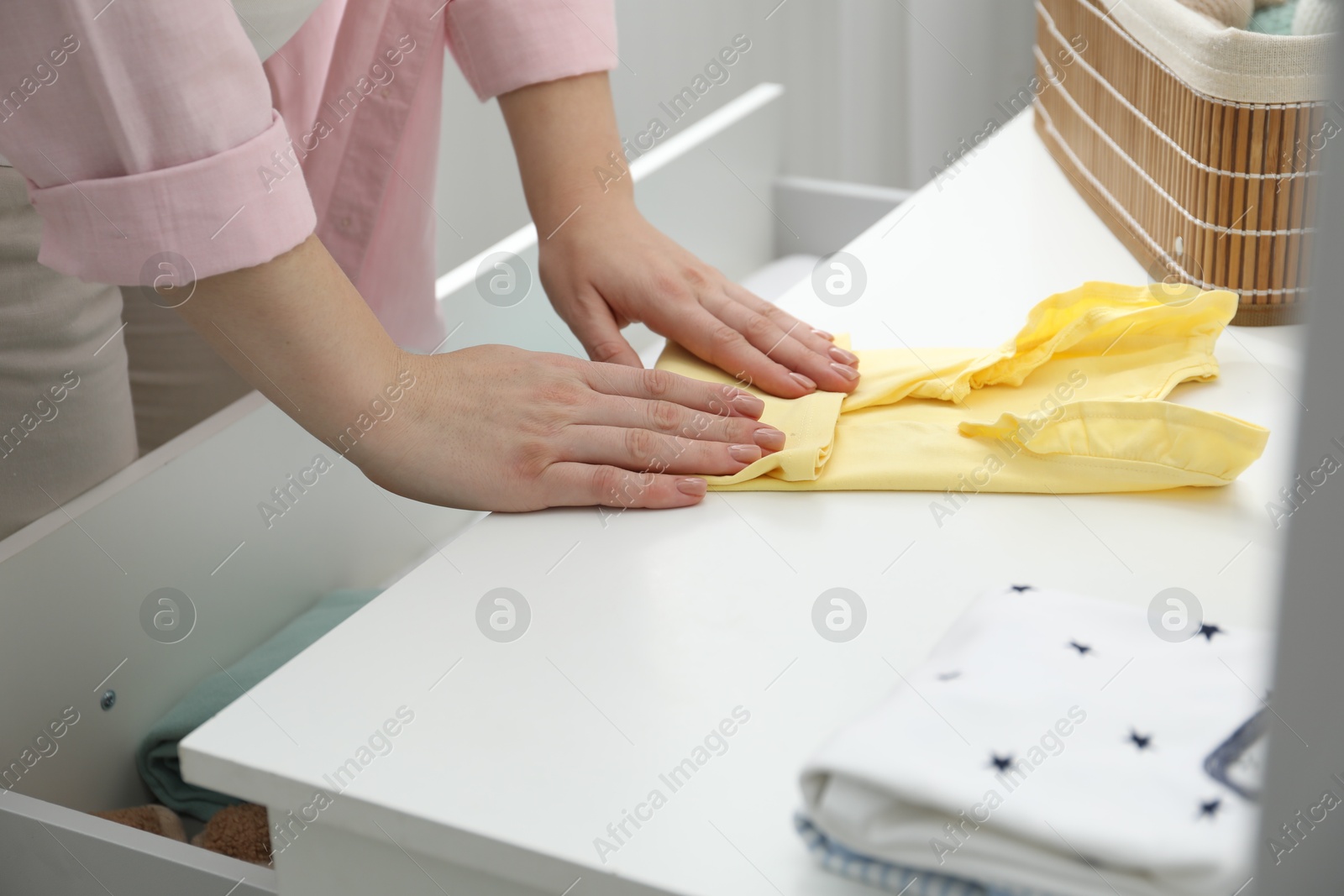 Photo of Woman folding baby clothes at home, closeup