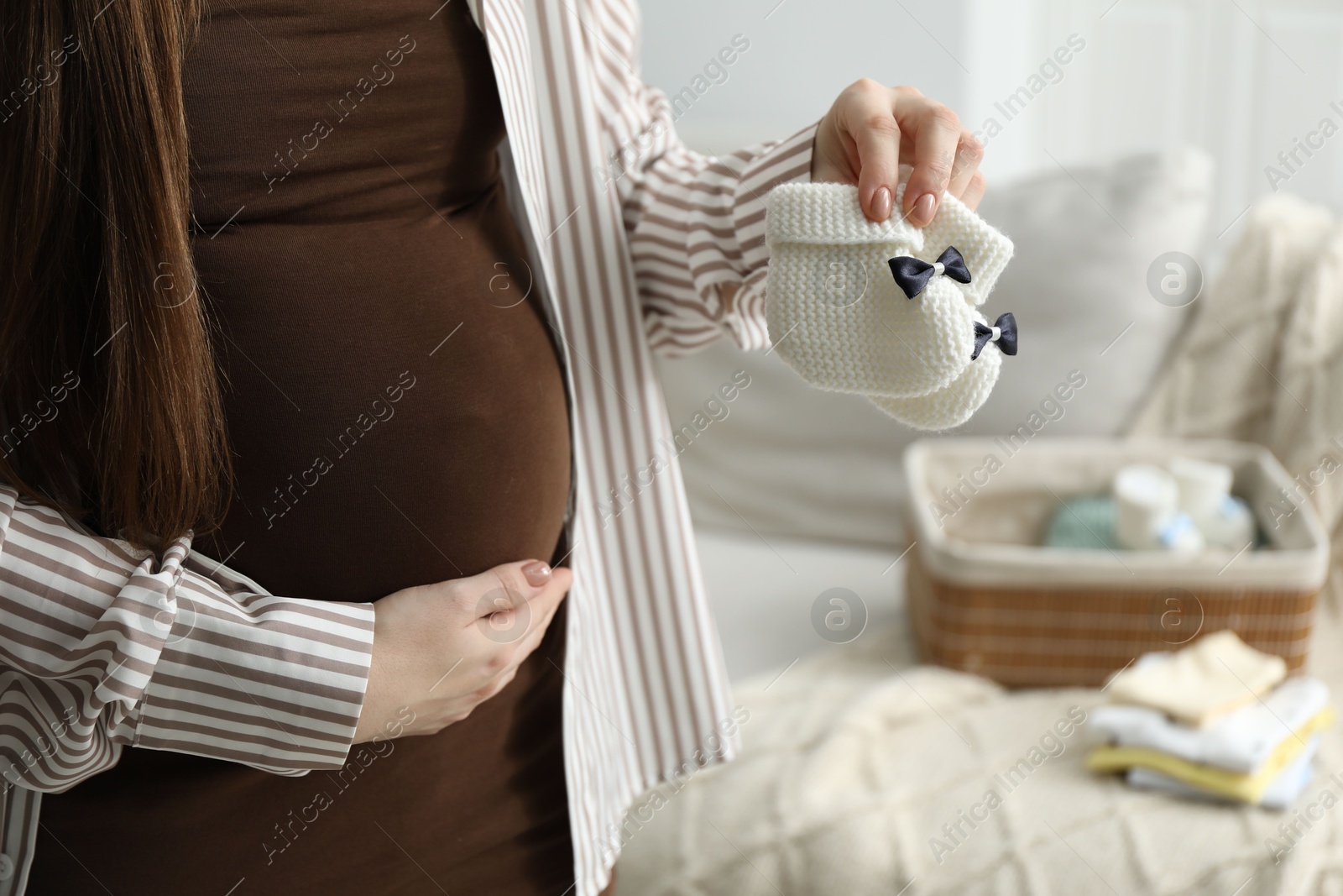 Photo of Pregnant woman with baby booties at home, closeup