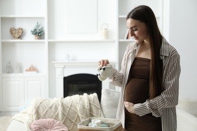 Photo of Pregnant woman with baby booties at home