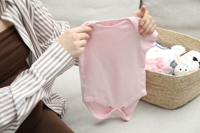 Photo of Pregnant woman with baby clothes on sofa at home, closeup