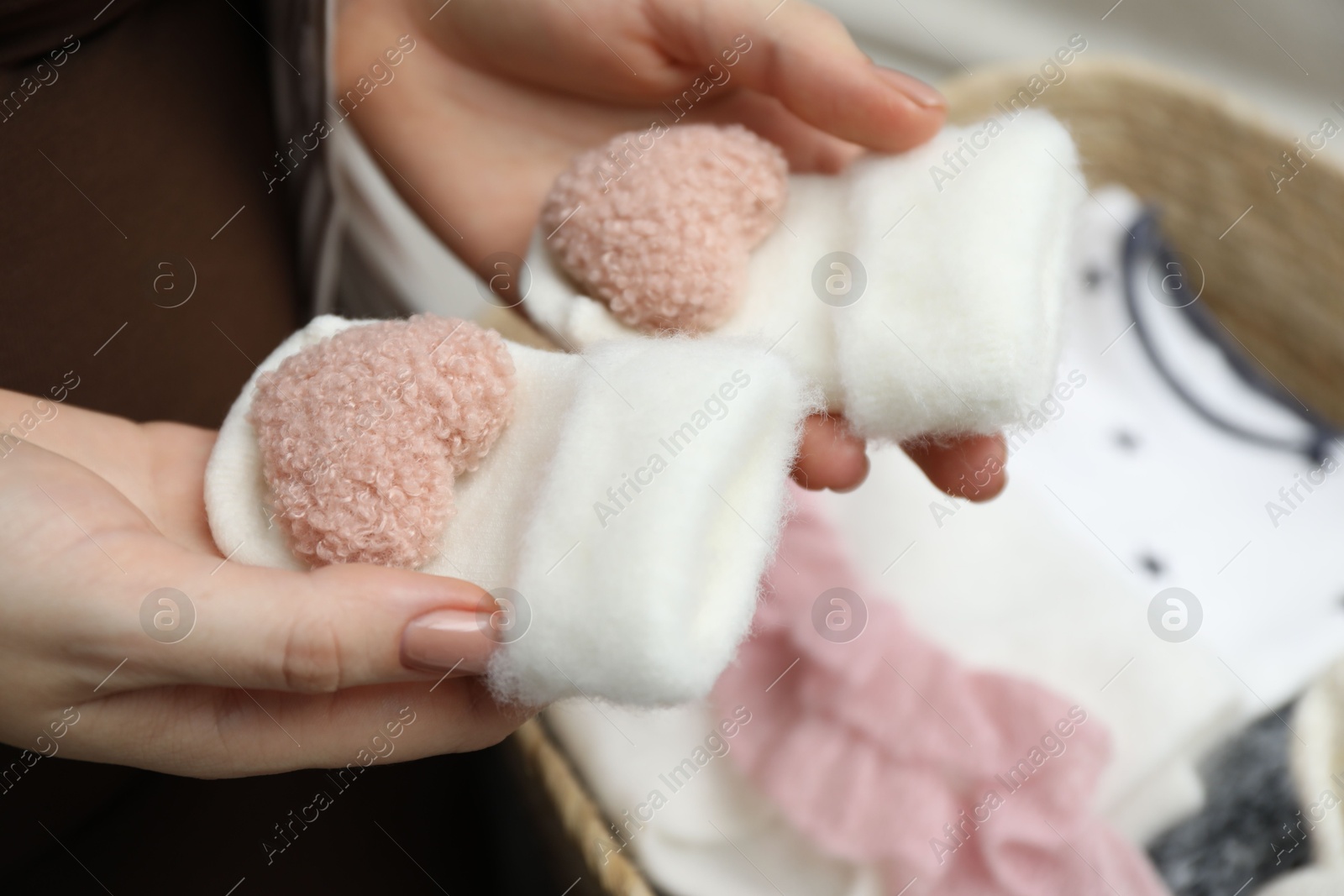 Photo of Pregnant woman with baby socks at home, closeup