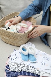 Photo of Woman with baby clothes on sofa at home, closeup