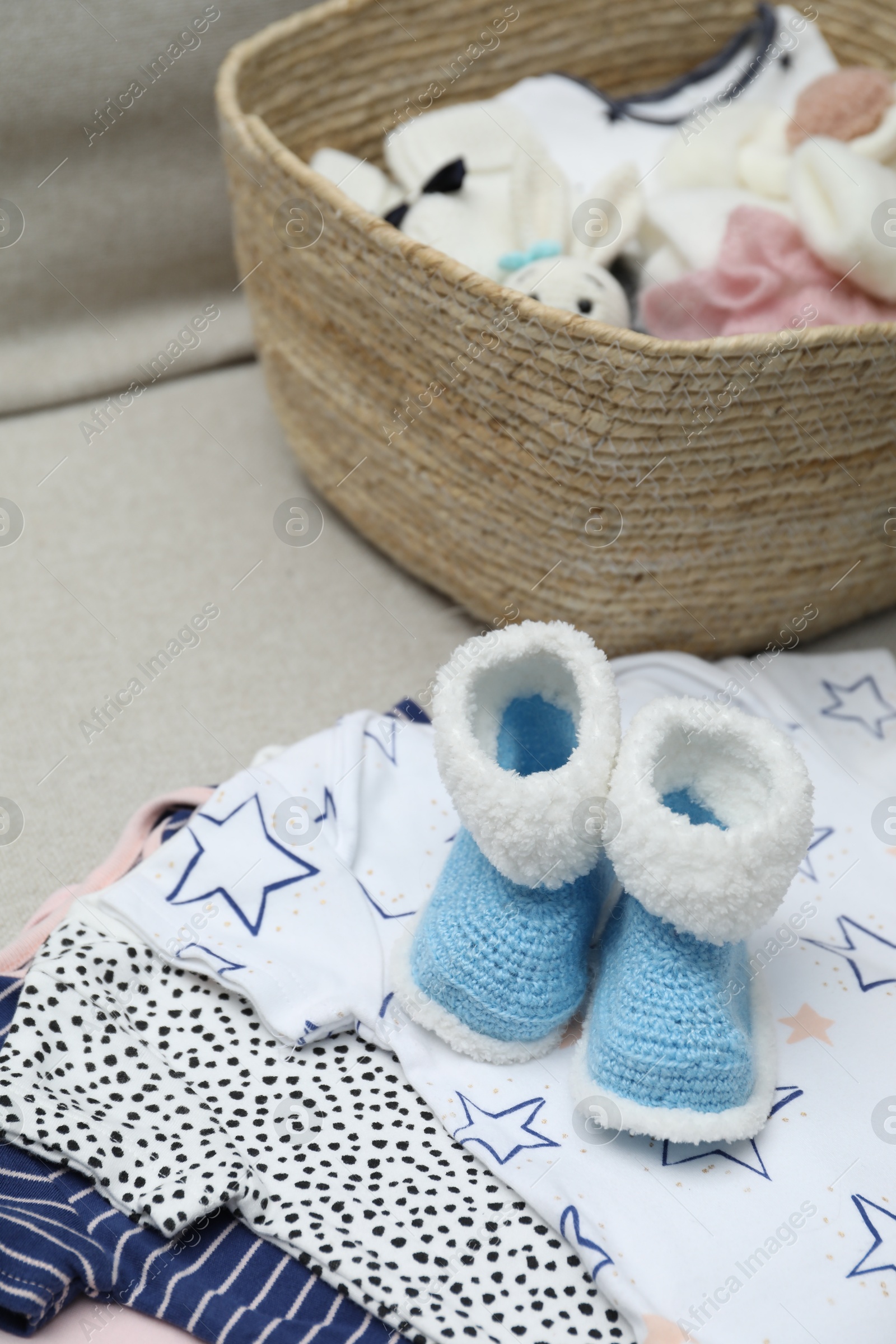 Photo of Baby booties and other clothes on sofa, closeup