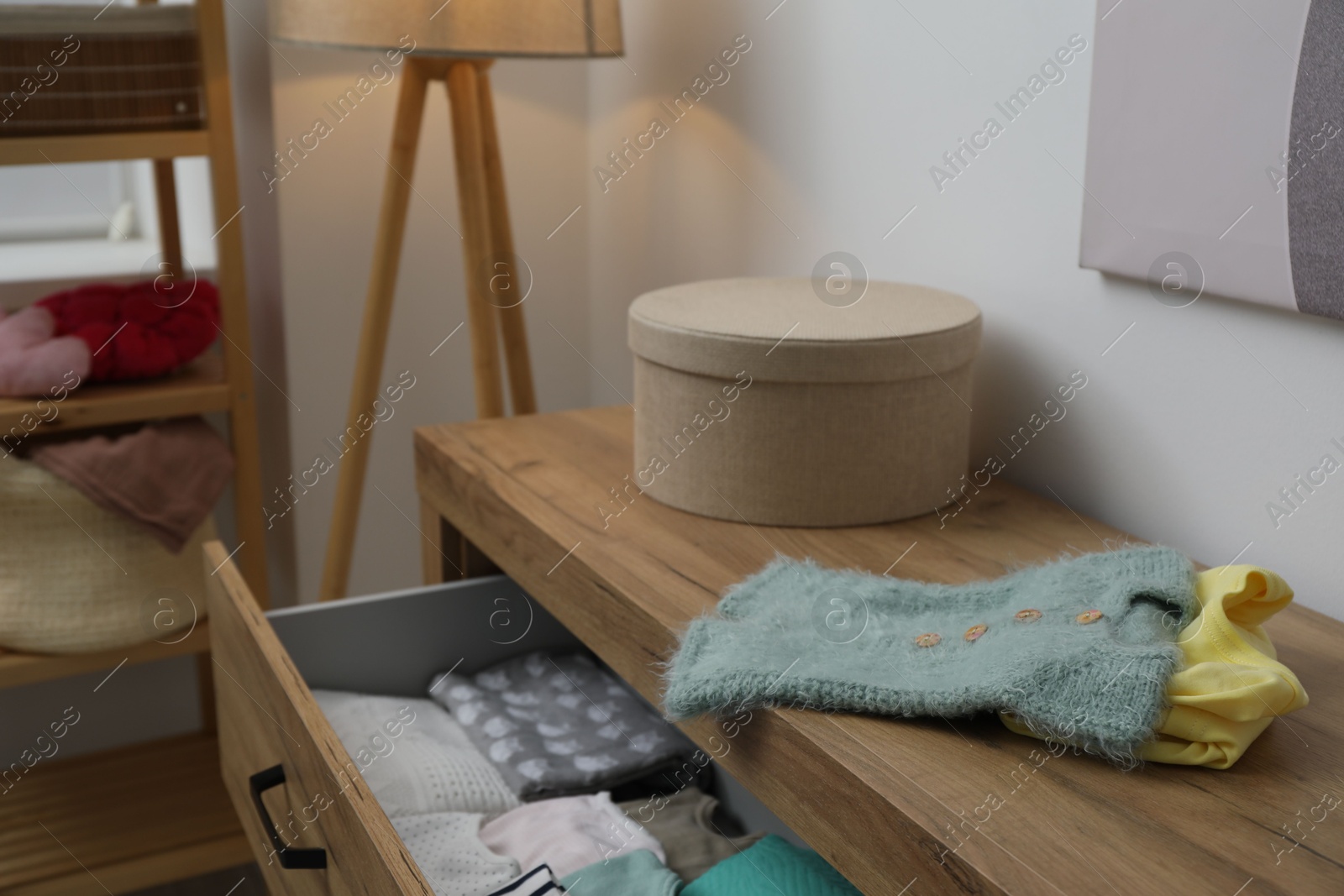 Photo of Baby clothes on wooden chest of drawers indoors