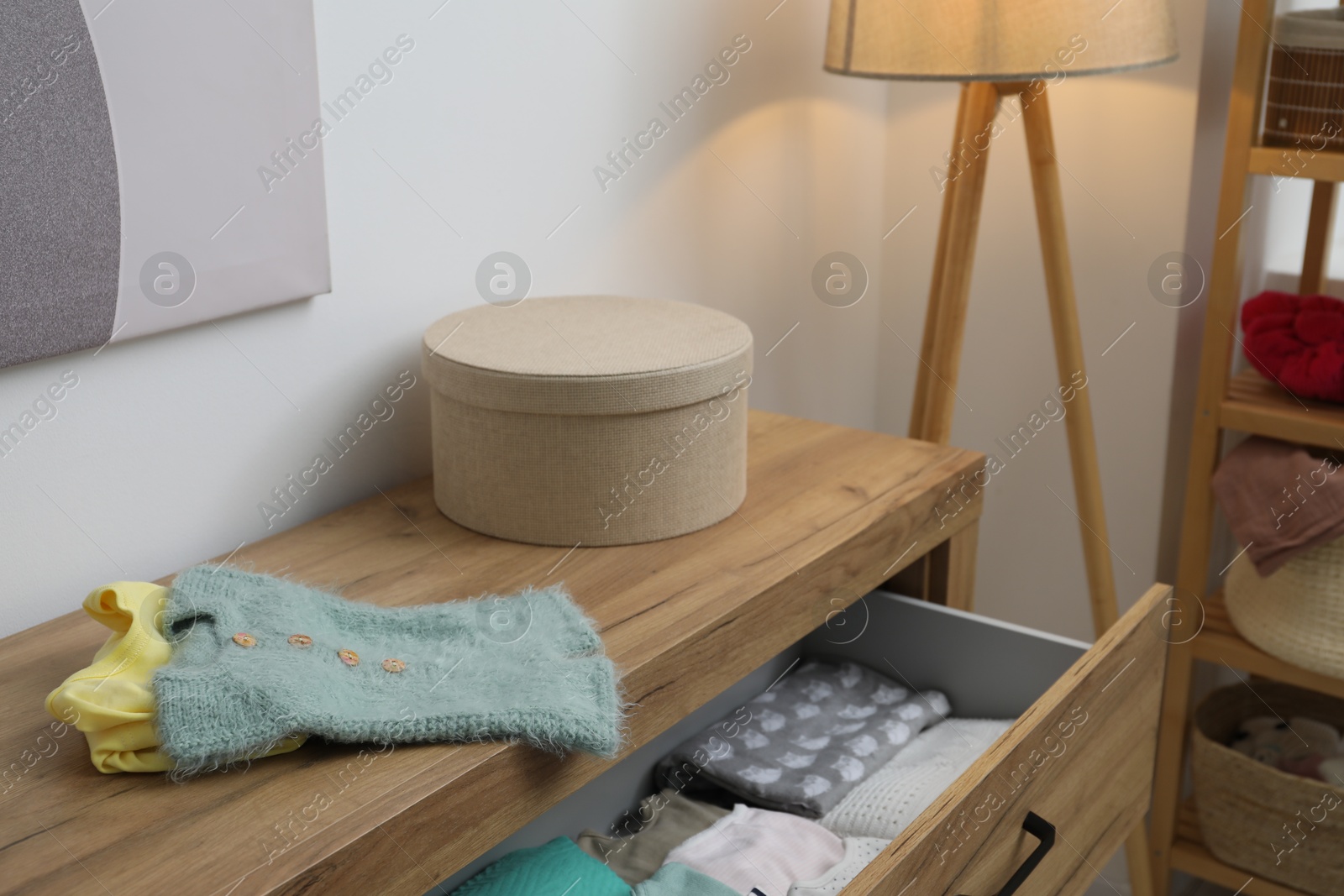 Photo of Baby clothes on wooden chest of drawers indoors