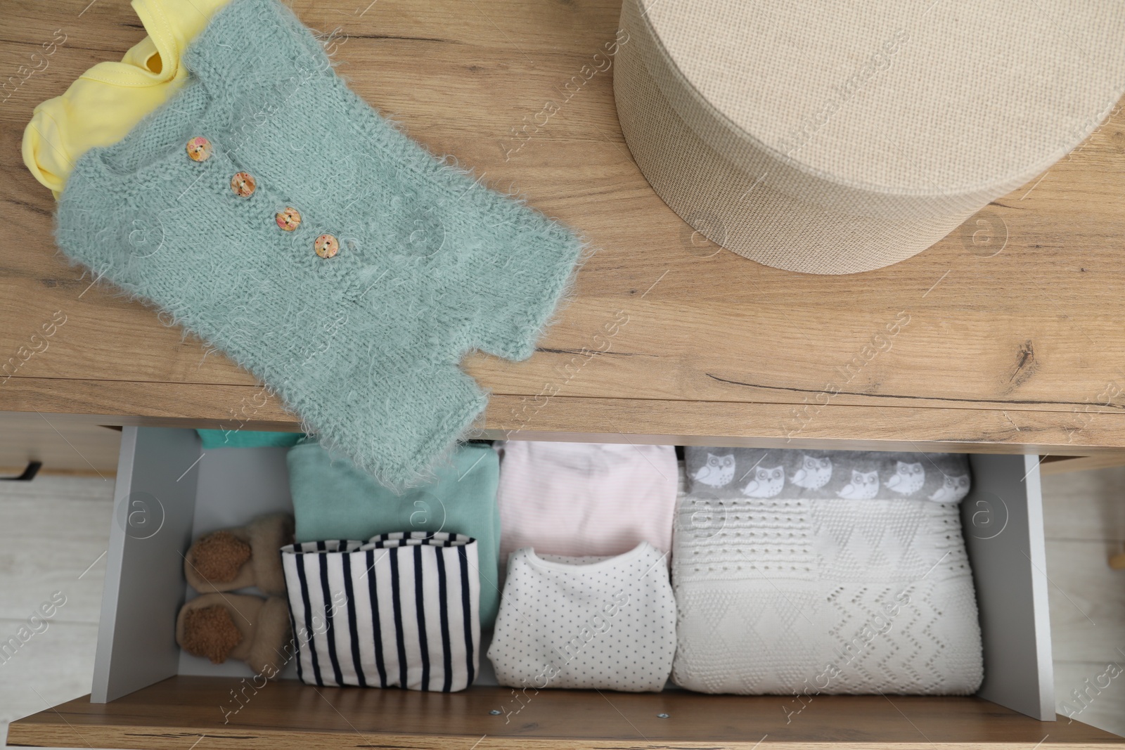 Photo of Baby clothes on wooden chest of drawers, top view