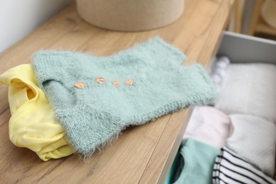 Photo of Baby clothes on wooden chest of drawers, closeup