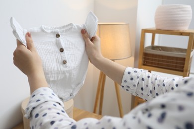 Photo of Woman with baby clothes at home, closeup