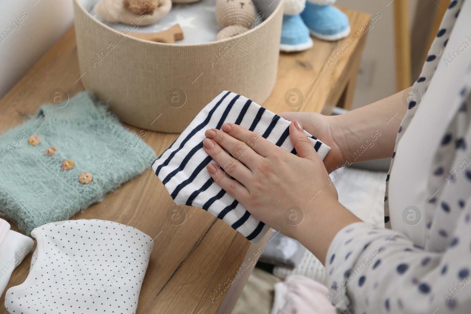 Photo of Woman with baby clothes at home, closeup