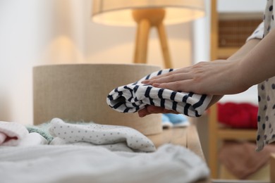 Photo of Woman with baby clothes at home, closeup